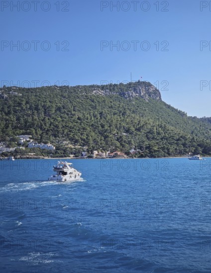 Vibrant seascape with a boat cruising away on the blue sea, leaving a white wake. Beautiful Turkish