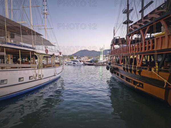 Kemer marina at dusk, filled with multiple docked boats. Lights of the harbor and the resort