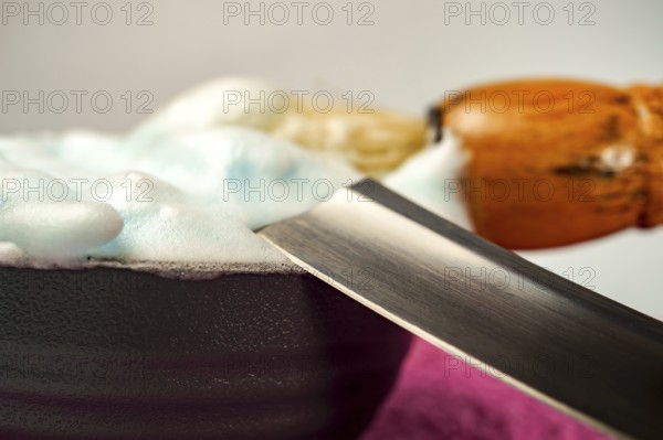 Shaving cream in bowl with straight razor and shaving brush, ready for barber to prepare customer