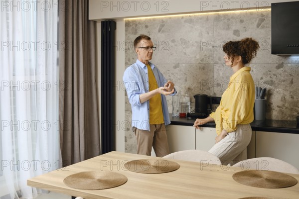 A couple engages in conversation near a kitchen counter, discussing ideas as they prepare for a