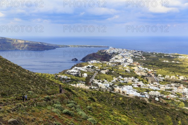Coastline with view of the village of Oia, hiker on hiking trail from Fira to Oia, Thira,