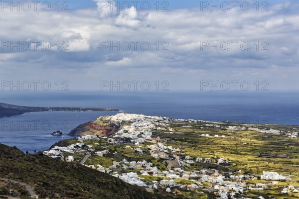 Coastline with view of the village of Oia, hiker on hiking trail from Fira to Oia, Thira,