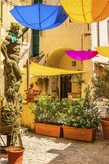 Coloured umbrellas cover a bronze statue in Via Cavour, Capoliveri, Elba Island, Tuscan Archipelago
