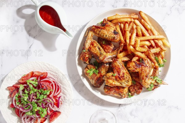 Delicious barbecue chicken wings, with French fries, salad and a refreshing drink, at a cozy table,
