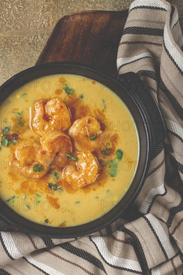 Creamy shrimp curry with spices, garnished with herbs, on a textured background, homemade, no