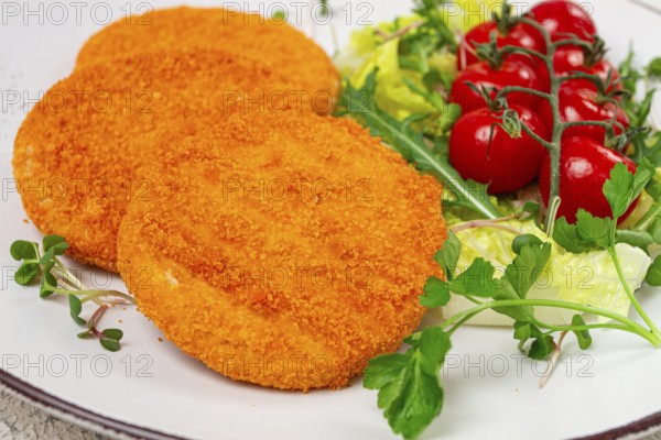 Crispy fried fish cutlets, fish burgers, on a white plate, with fresh lettuce leaves, arugula and
