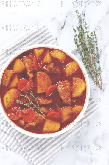 Meat goulash with potatoes and carrots, sweet peppers, in a saucepan, top view, traditional