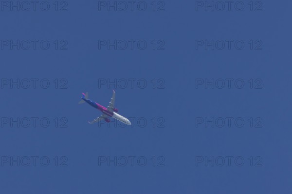 Airbus A321 jet aircraft of Wizz Air airlines in flight in a blue sky, England, United Kingdom