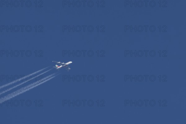 Airbus A380 jet passenger aircraft of Emirates airlines in flight in a blue sky with vapour trails