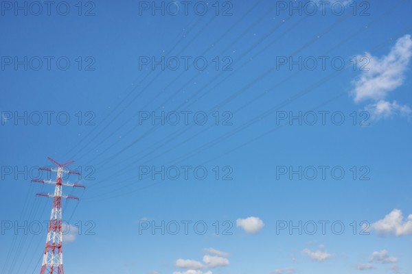 An extremely high electricity electricity electricity pylon, marked white and red, on the banks of