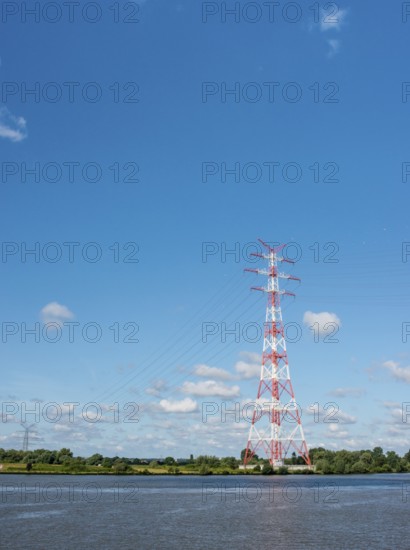 An extremely high electricity electricity electricity pylon, marked white and red, stands on the