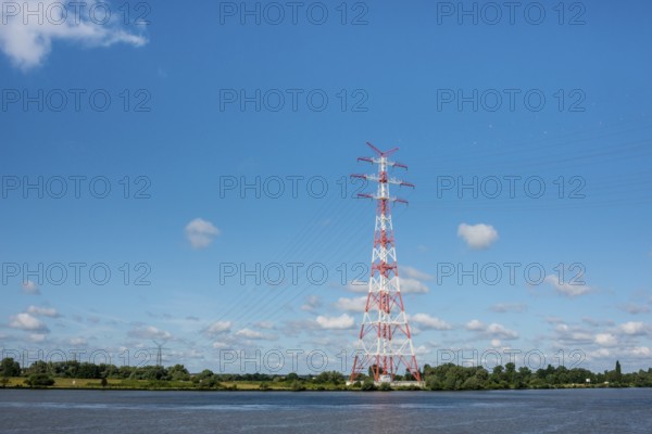 An extremely high electricity electricity electricity pylon, marked white and red, stands on the