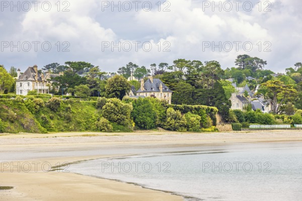 House by a sandy beach by the sea with lush green trees at the coast, Morgat, Crozon peninsula,