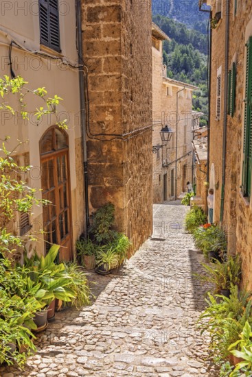 Empty cobblestone alley with beautiful stone houses a sunny hot day in an old spanish village,