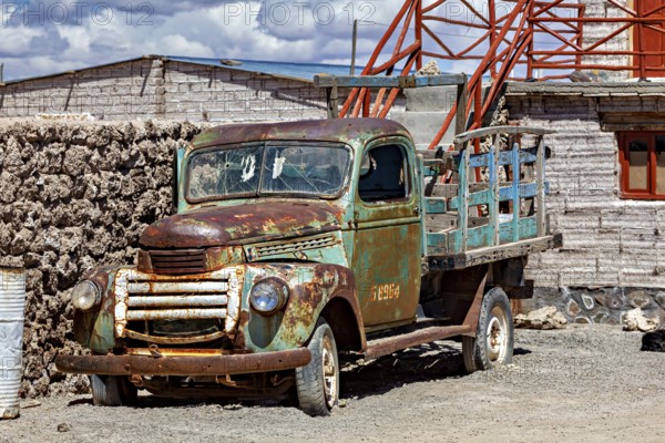 Rusty historic lorry next to an old brick building with outside stairs under a blue sky, Old lorry