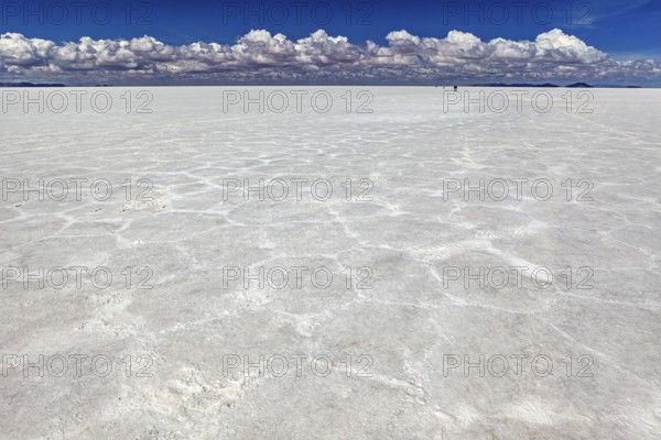 Salt crust with hexagonal patterns under a sky full of clouds, conveying endless expanses, The