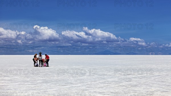 Group of people around a table on a vast white salt flat under a blue sky, The endless expanses of