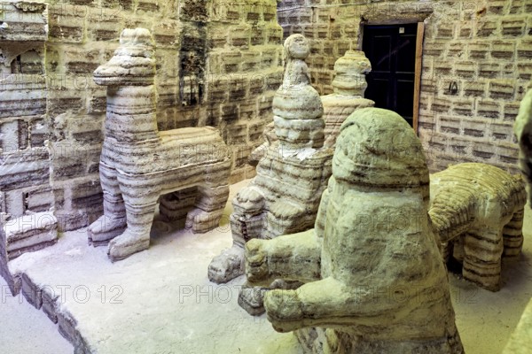 Beige stone sculptures of animals in a rustic room with patterned brick walls, The salt hotel in