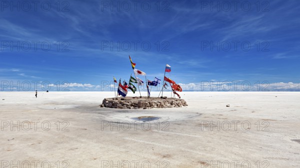 Flags in a vast salt lake under a clear blue sky with scattered clouds, international flags in the