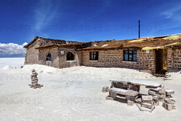 Rustic stone house in a desert-like landscape with blue sky and white ground, the salt hotel in the