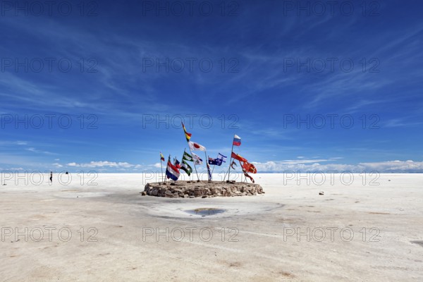 Flags in a vast salt lake under a clear blue sky with scattered clouds, international flags in the