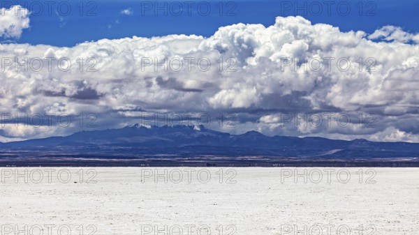 Majestic cloud formation over a flat, white salt landscape with a mountain backdrop, The endless