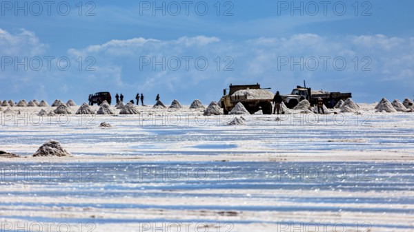 Vehicles and people move between salt hills on a shiny salt surface, The endless expanses of the