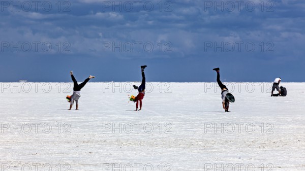 People doing handstands on a vast salt flat under a dramatic sky, The endless expanses of the salt