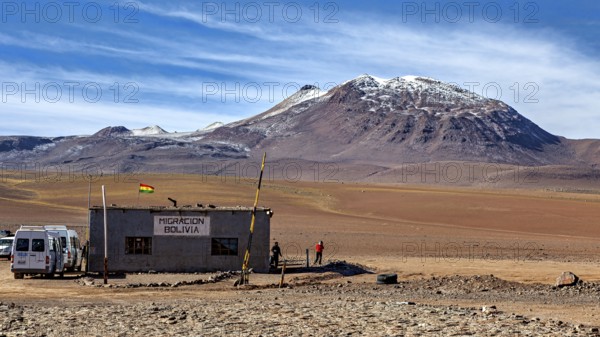 A small migration building in a barren desert landscape with mountains in the background, The small
