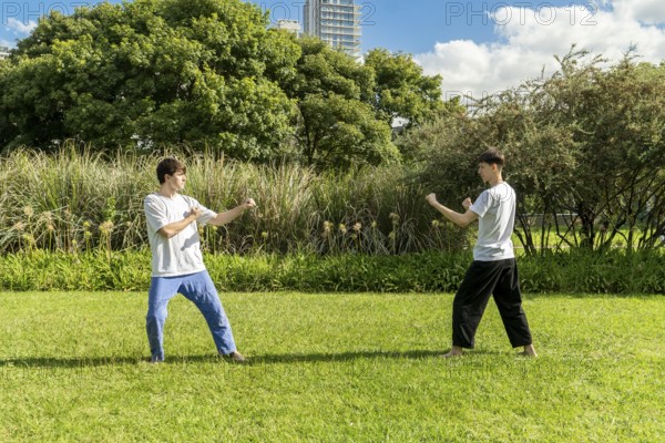 Two young men prepare to start a taekwondo fight outdoors