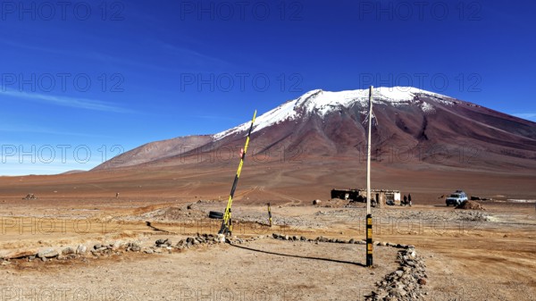 Border area in a treeless desert landscape with a snow-capped mountain and clear blue sky, The