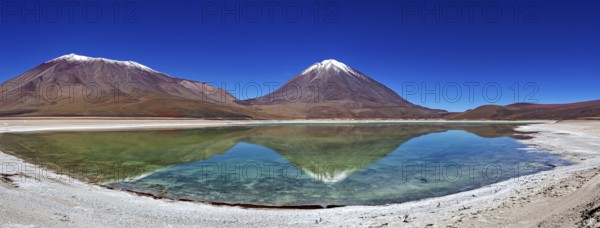 Broad mountain backdrop with two snow-covered peaks reflected in a calm lake, The Laguna Colorada