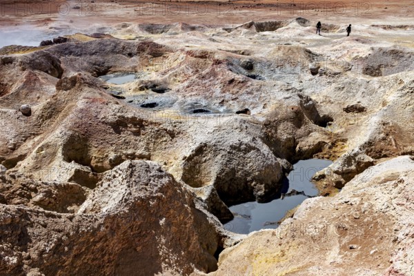 Hot springs with mineral colours in a desert, group of people in the background, The mud volcanoes