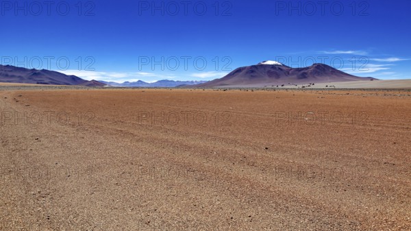 A wide, dry expanse of sand with a mountain on the horizon under a clear blue sky, The landscape of