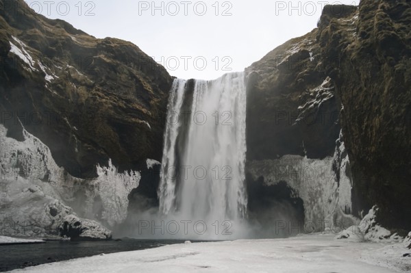 The mighty Skogafoss waterfall in winter. Roaring masses of water meet ice and rock. Skogar,