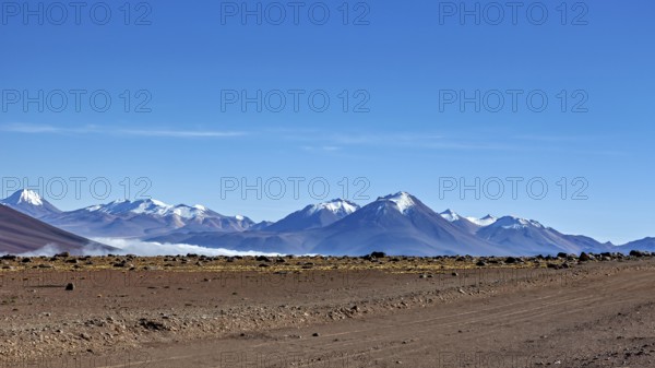 Vast dry desert landscape with snow-capped mountains and clear blue sky, The landscape at San Pedro