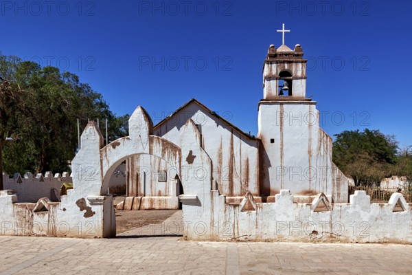 Rustic church with a striking cross under a bright blue sky and clear lines, The church of San