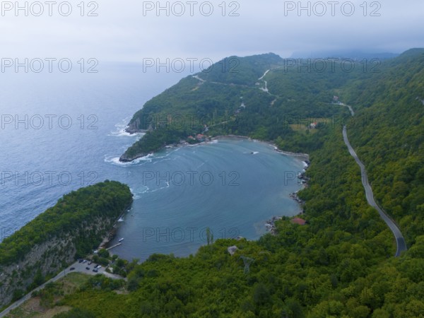 Aerial view of a quiet coastline with wooded mountains and a winding road, aerial view, Gideros