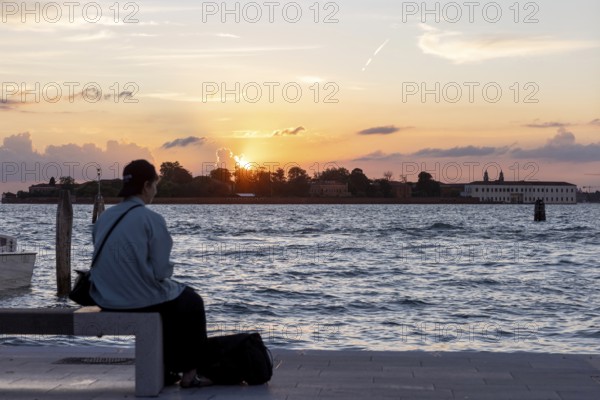 Venice, Italy - 2 September 2025: Passengers sit on the jetty at the Lido at sunset, waiting for