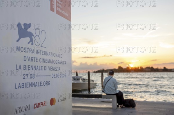 Venice, Italy - 2 September 2025: Passengers sit on the jetty at the Lido at sunset, waiting for
