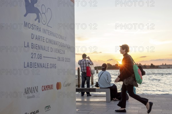 Venice, Italy - 2 September 2025: Passengers sit on the jetty at the Lido at sunset, waiting for