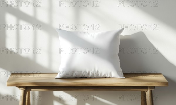 A white pillow sits on a wooden bench in front of a white wall. The pillow is empty and the bench
