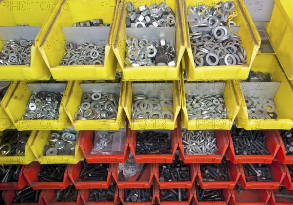 Full frame industrial background showing yellow and red boxes filled with lots of various screws