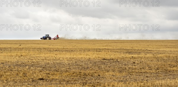 Stormy farmland scenery showing a Tractor on a stubble field in Hohenlohe, an area in Southern