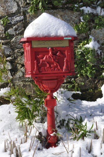 Vintage red mailbox under the snow, Ornate red mailbox covered in snow against a stone wall with
