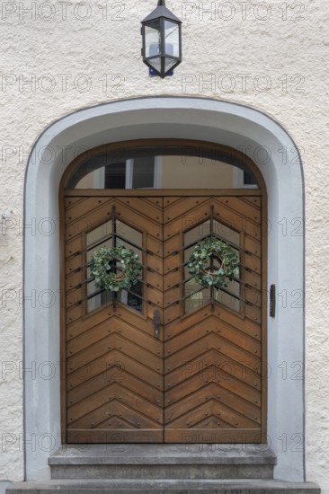 Façade with wooden gate, lantern and ivy wreaths, Kempten, Allgäu, Bavaria, Germany