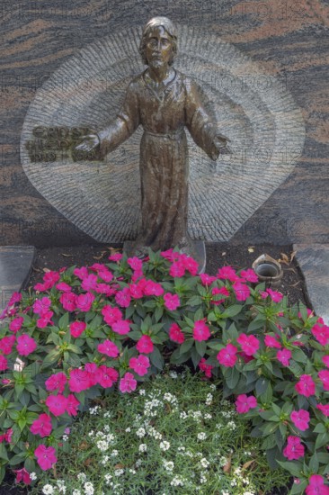 Gravesite with Christ figure and floral decorations, noble lily (Impatiens New Guinea) Catholic