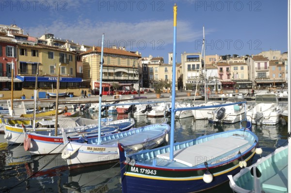 Cassis, the port, A vibrant harbor scene with colorful boats floating in calm water, lined by