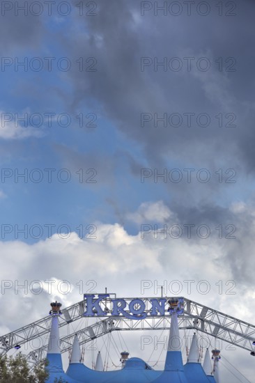 Circus tent, circus tent with luminous lettering in front of a blue sky with white and grey clouds,