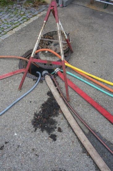 Water hoses and warning triangle on tarmac above open gully, Circus-Krone, Kempten, Allgäu,